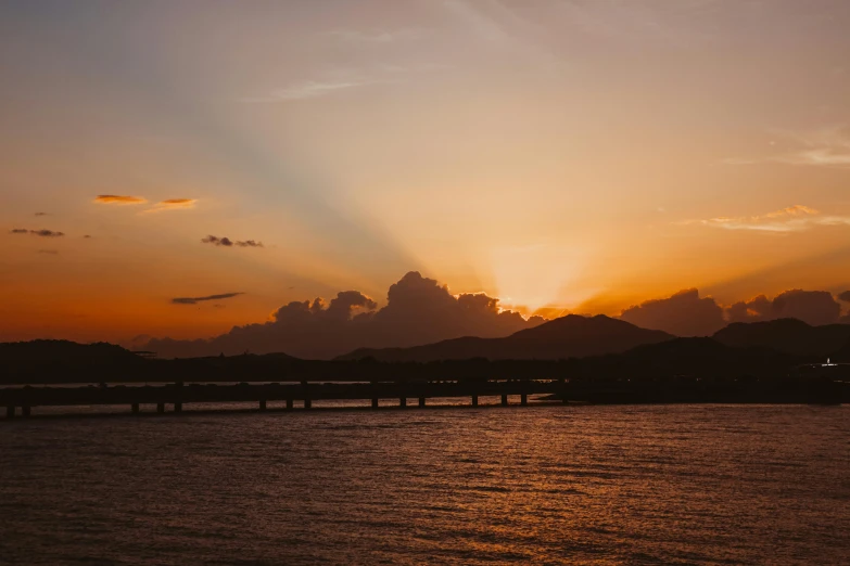 a beautiful sunset over the ocean near a mountain