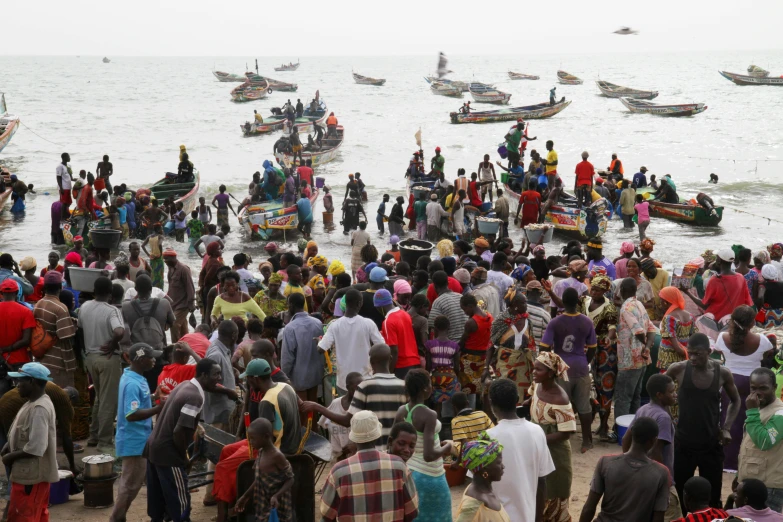 large crowd of people standing around on the beach