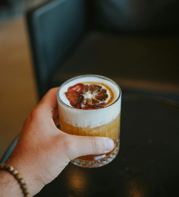 a person is holding a drink that has fruit on the top