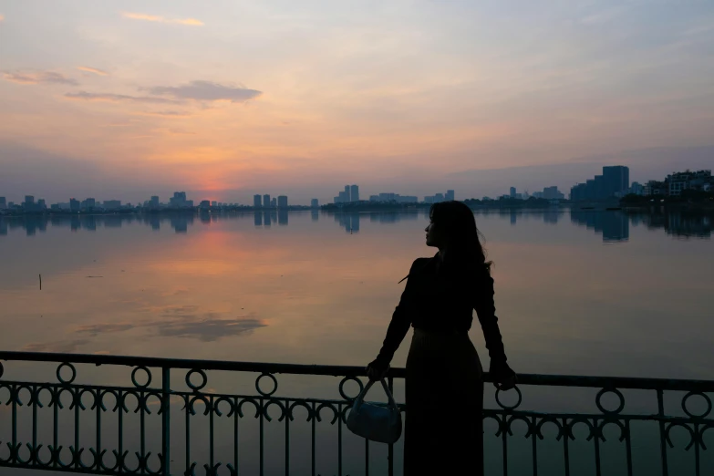 the woman stands by the water and looks into the distance