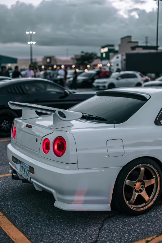 the back end of a white car parked in a parking lot