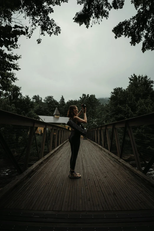 a woman taking a po on a bridge with her camera