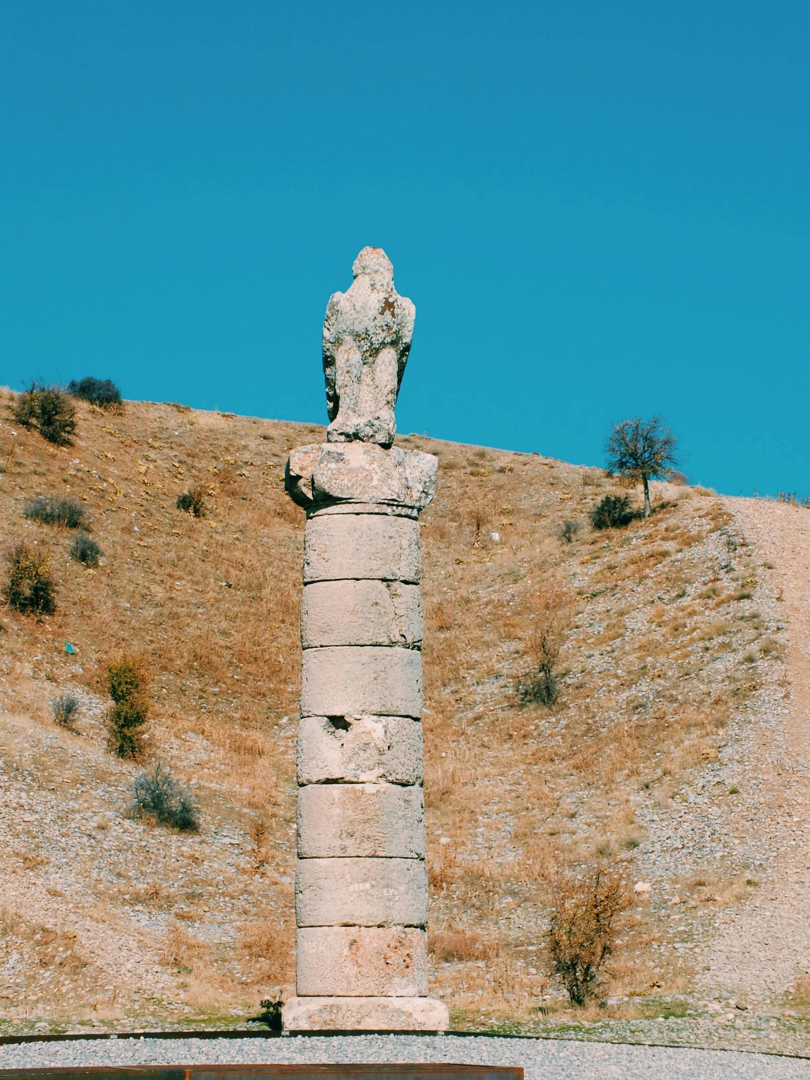 a stone statue in the middle of an arid field