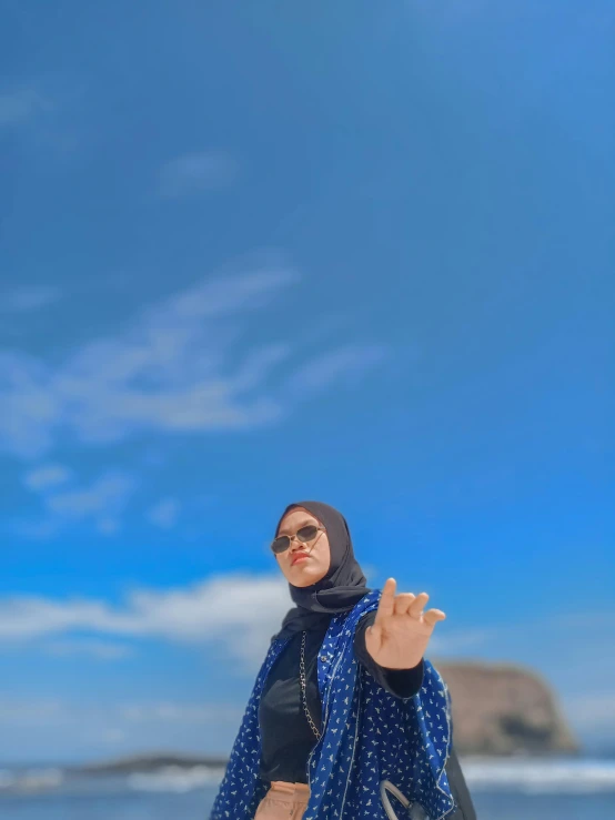 a woman wearing a blue and white scarf standing on the beach