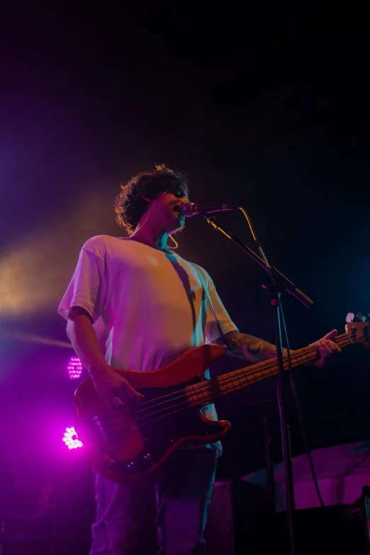 the young man is playing a bass in front of a microphone