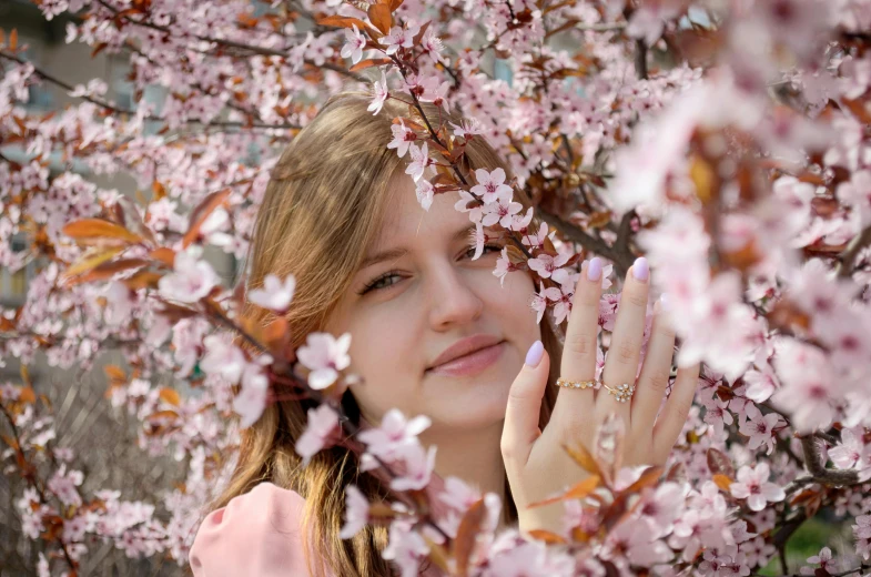 a woman is peeking out from behind a tree