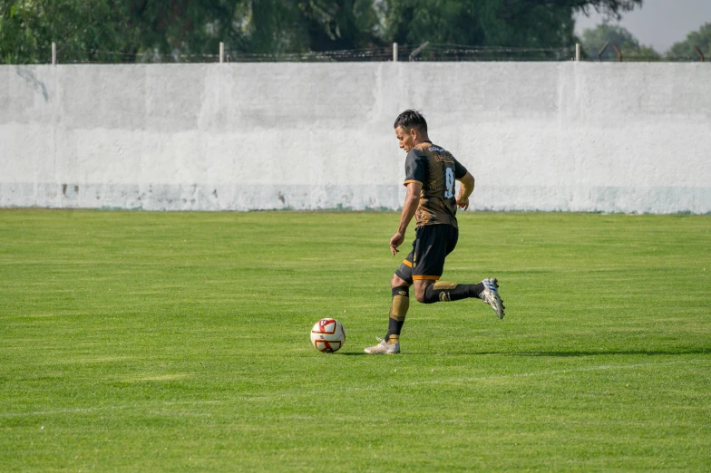 a male soccer player running and kicking a ball