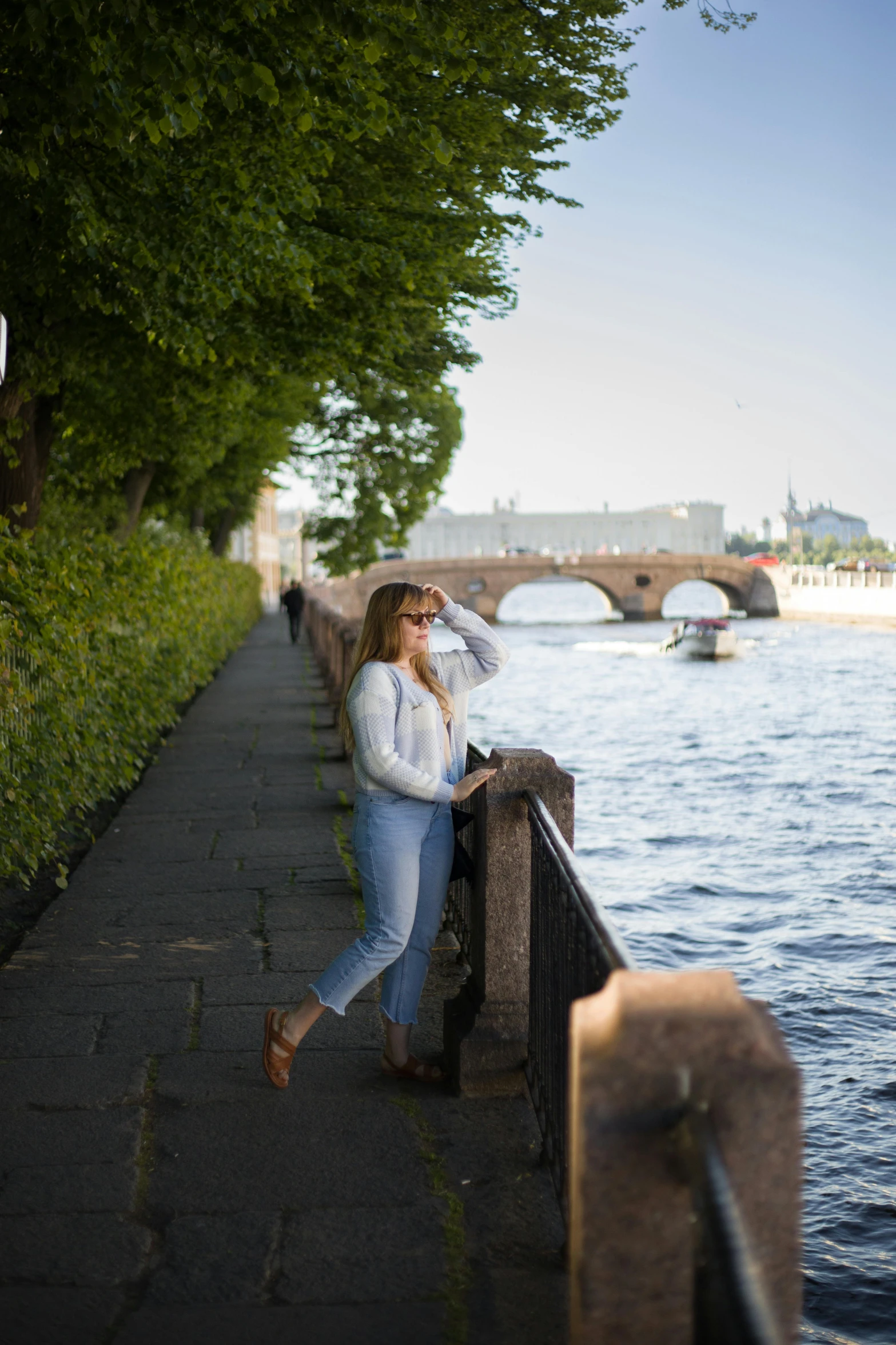 a woman standing on the side of a walkway next to a river