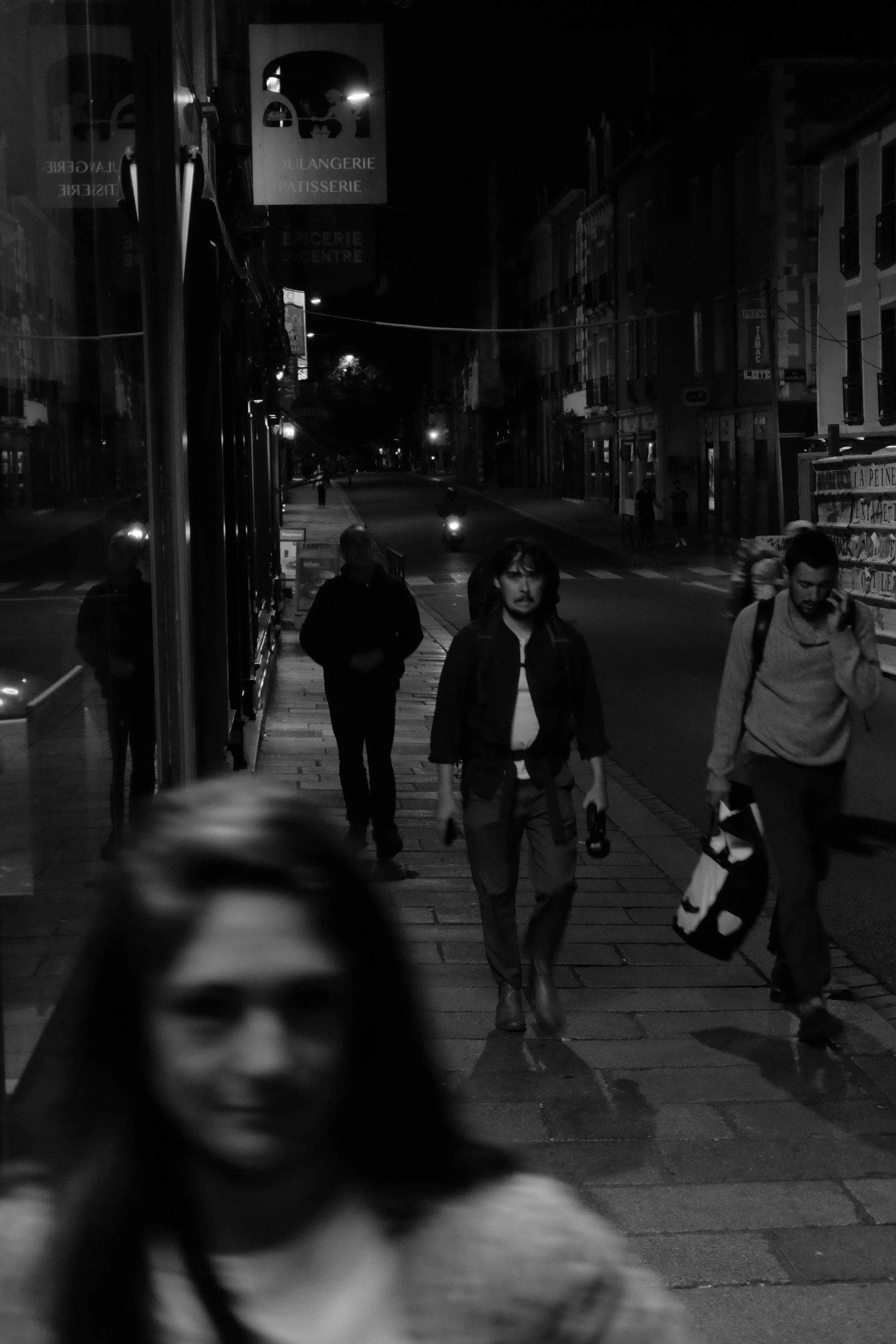 black and white pograph of people walking on sidewalk