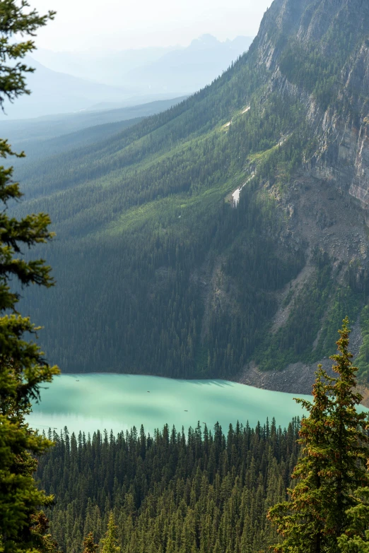 a mountain view with trees near by and blue water