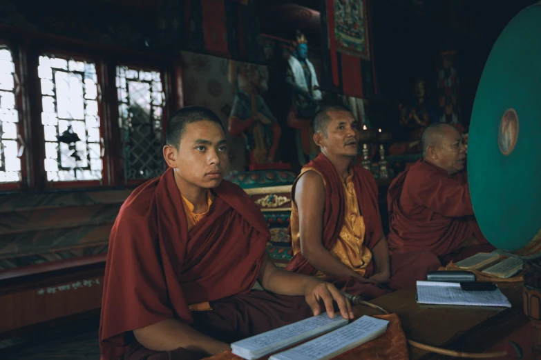 three monks sit in a row near each other