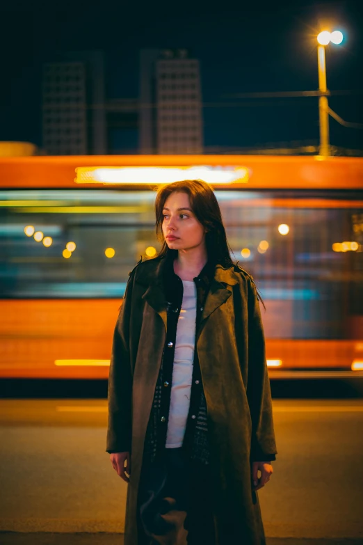 a woman in a long trench coat standing on a sidewalk