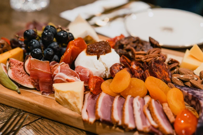 a large wooden plate topped with meat and cheese