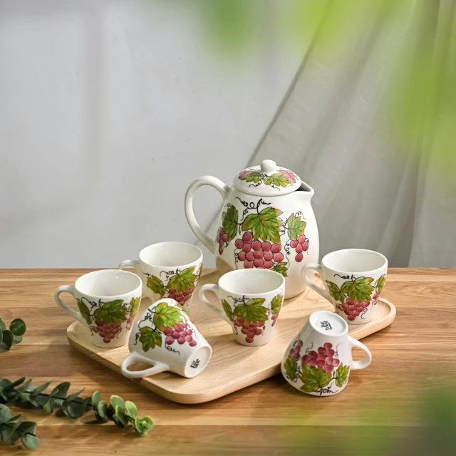 a tray with six matching cups and one teapot covered in leaves