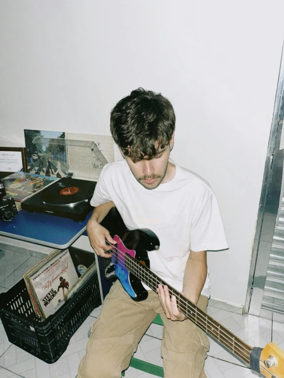 a young man sits on the floor while playing a guitar