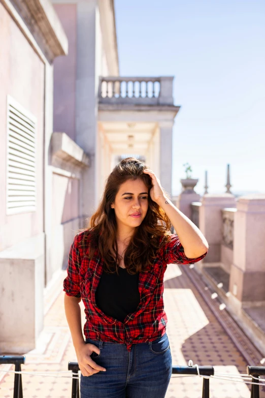 a woman leaning on a rail holding her hands on her head