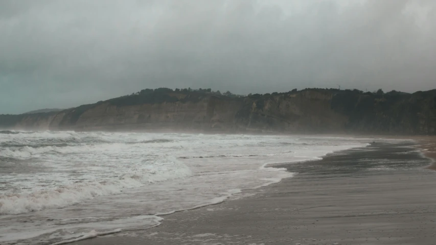 some very big waves by the shore by some cliffs