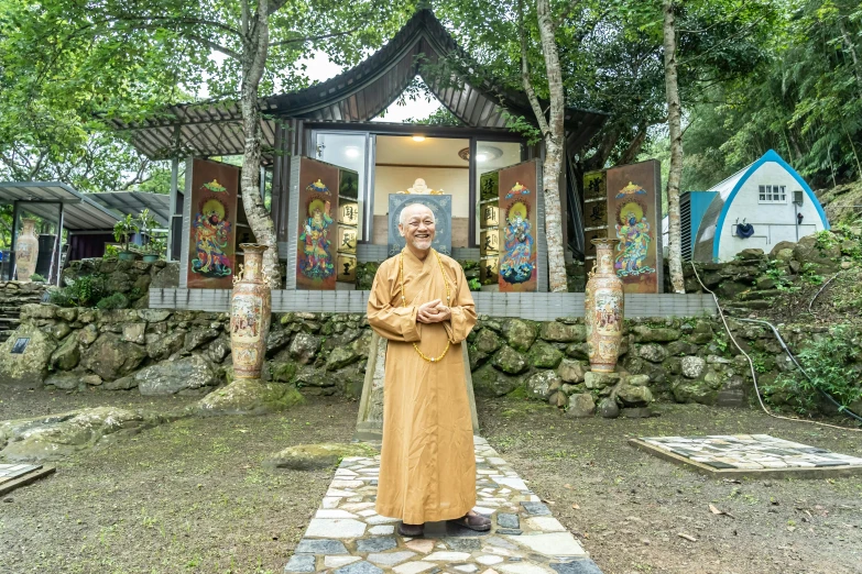 an old buddhist monk stands in front of the shrine