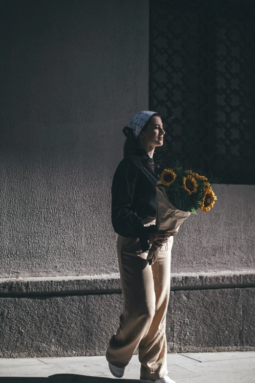 a woman holding flowers is walking down the street