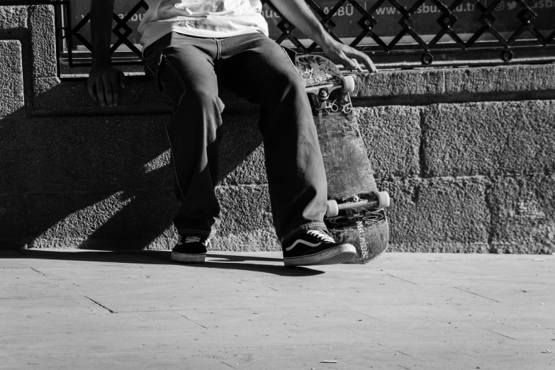 a boy in white shirt sitting on curb with his skateboard