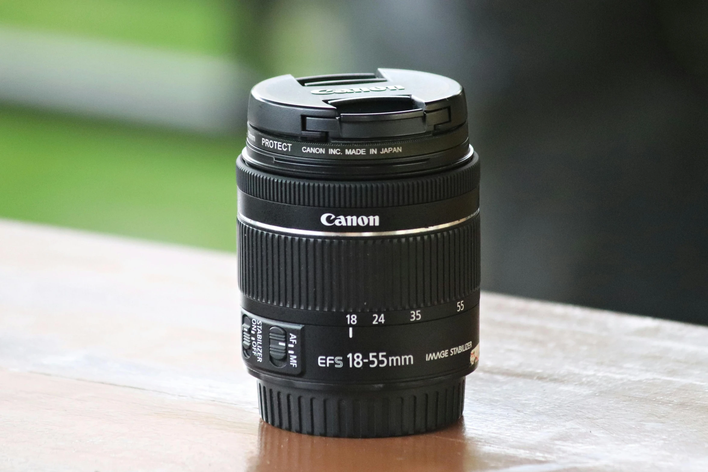 a camera lens on a wood table with its hood down