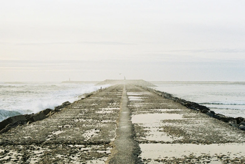 some sea and concrete and water with people on a hill