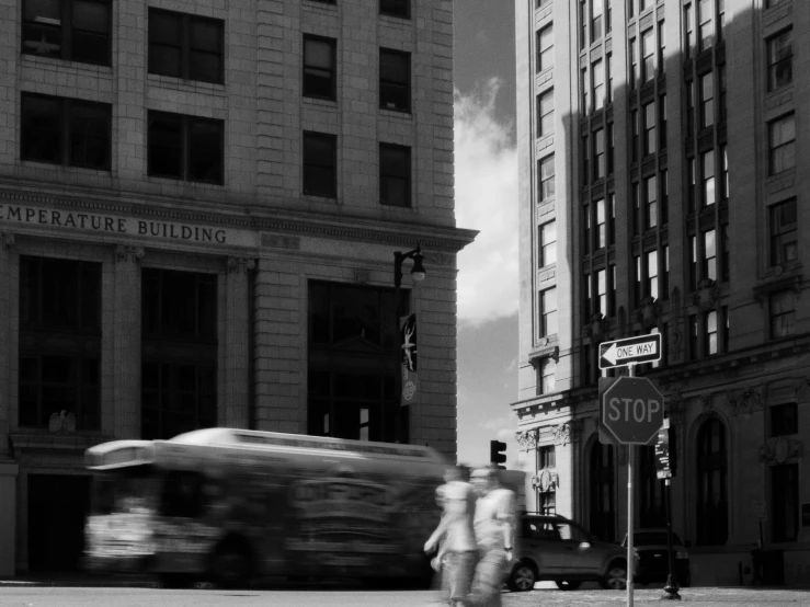 two people are crossing a street in front of a bus