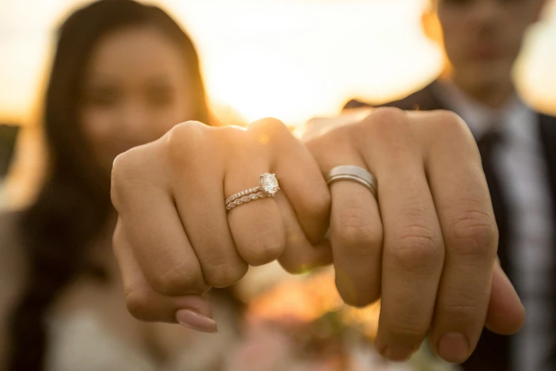 a couple holding hands with a wedding ring on them