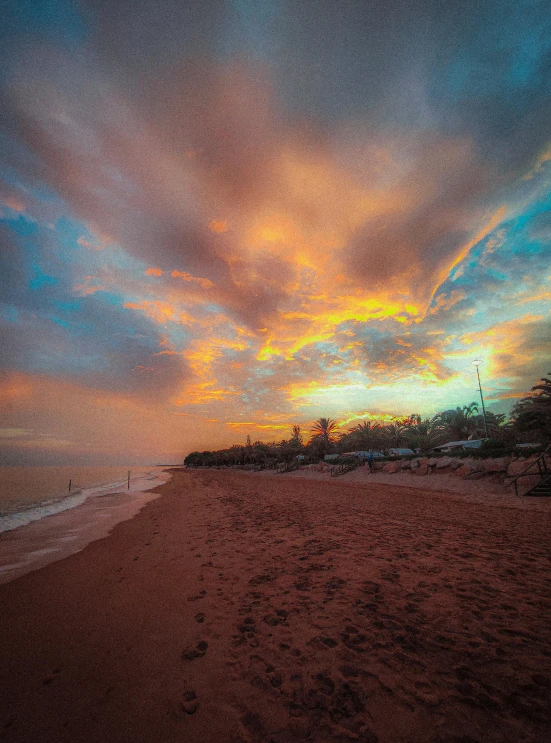 a beach in the early evening with clouds on it