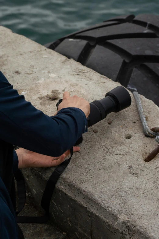 the hand is holding on to a rope that has been tied to a wall by a river