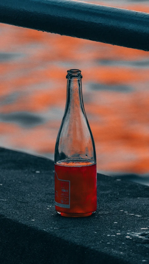a wine bottle and its red liquid on the ground