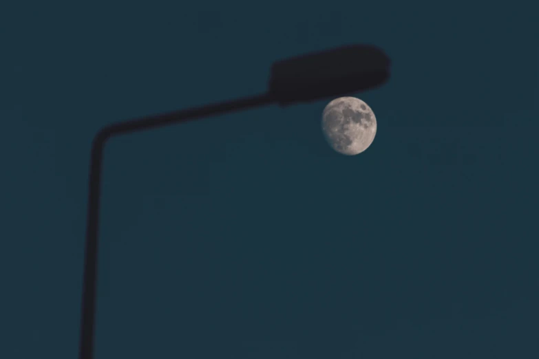 a street light next to a full moon