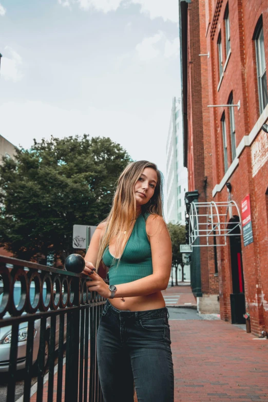 a woman standing next to a fence near a tall building