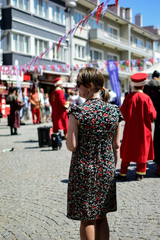 a woman in a black and white dress stands on the side walk