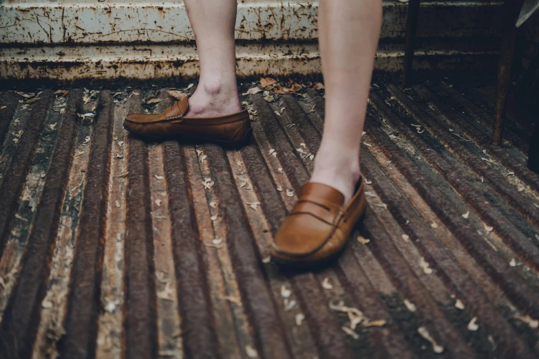 someone standing in front of a rusty staircase wearing shoes