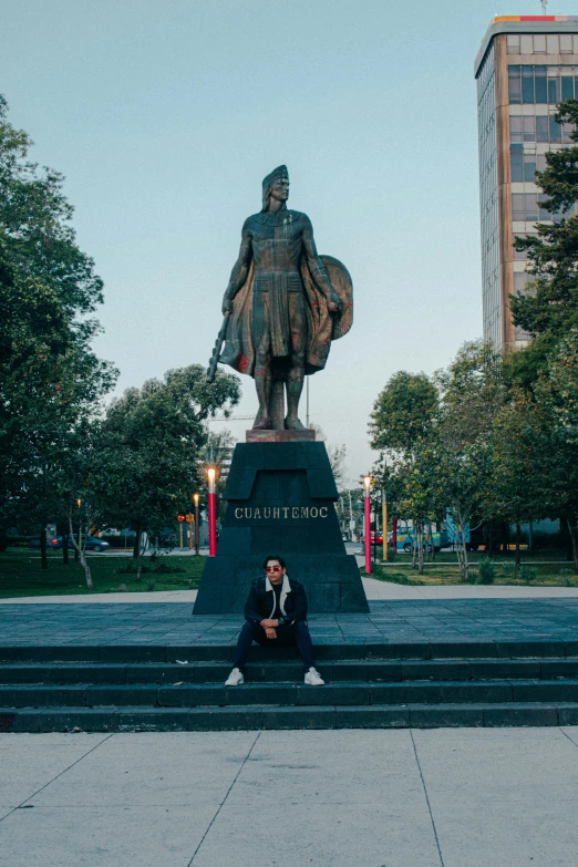 a person sitting next to a very large statue