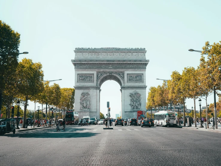 a group of cars driving in front of a tall archway