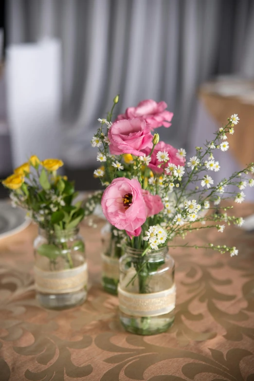 two glass jars holding different types of flowers