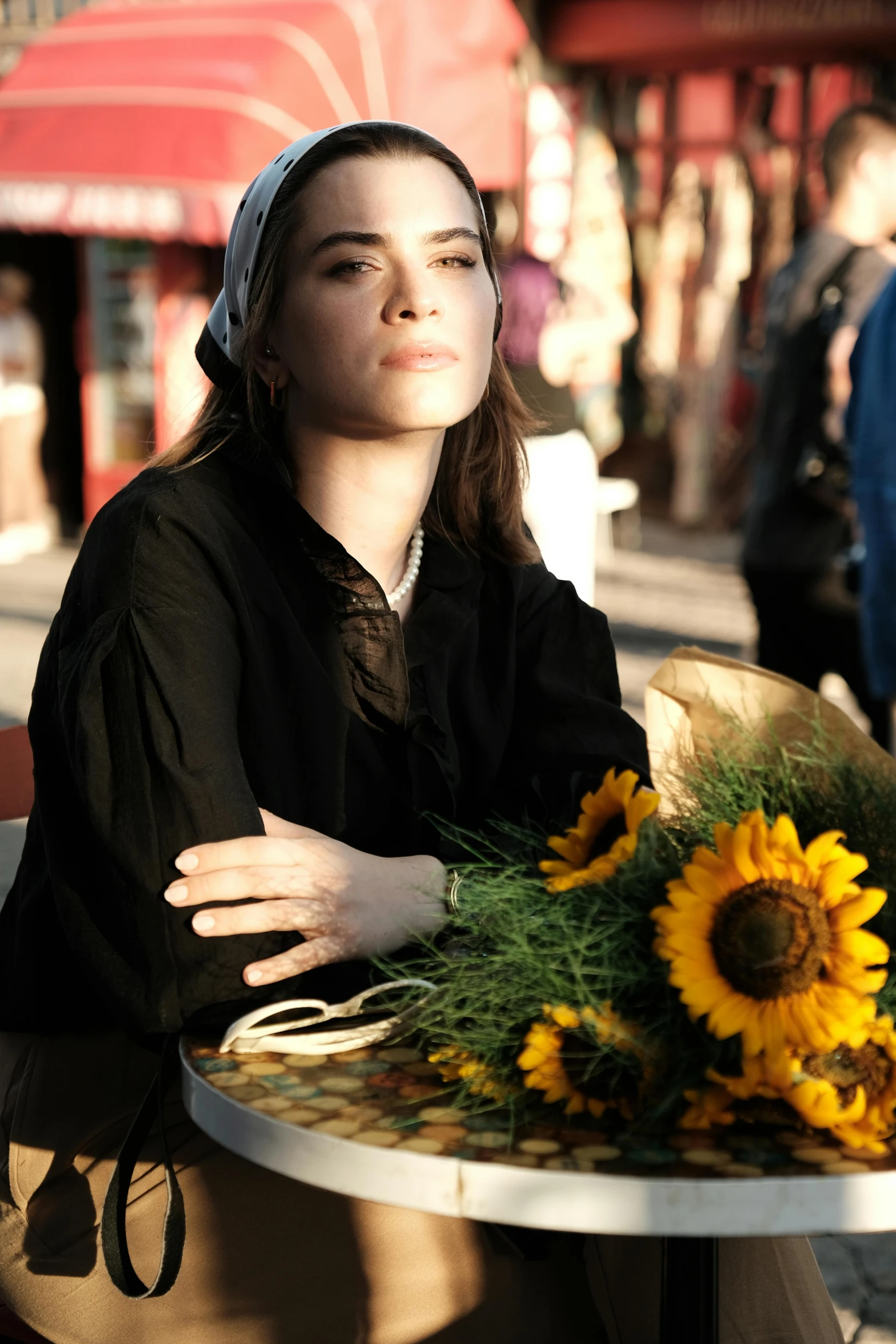 a girl in black sitting in a cafe table with a sunflower on it