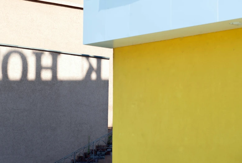 a building with two different colors and shadows, and a street sign on the front