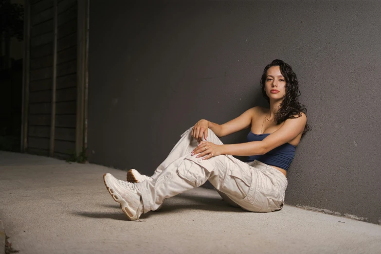 a woman wearing white pants, sitting on the ground