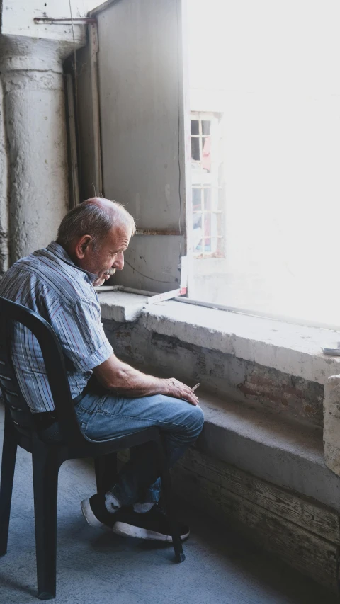 a man sitting on a chair looking out a window