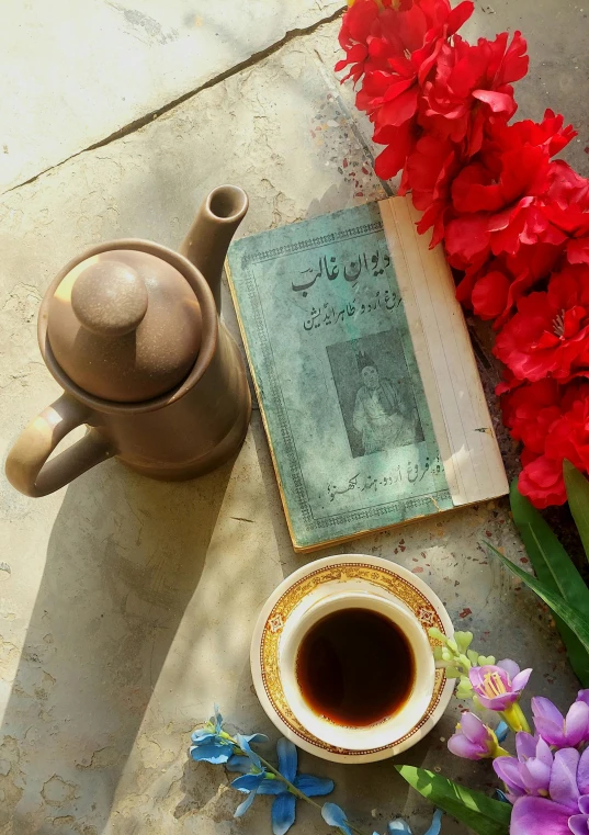 the teacup is sitting next to the book with flowers
