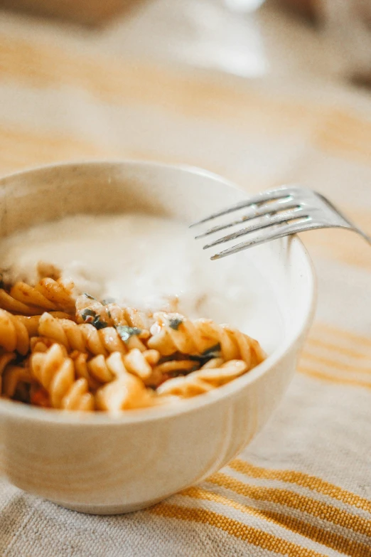 a bowl full of noodles with a fork resting in it