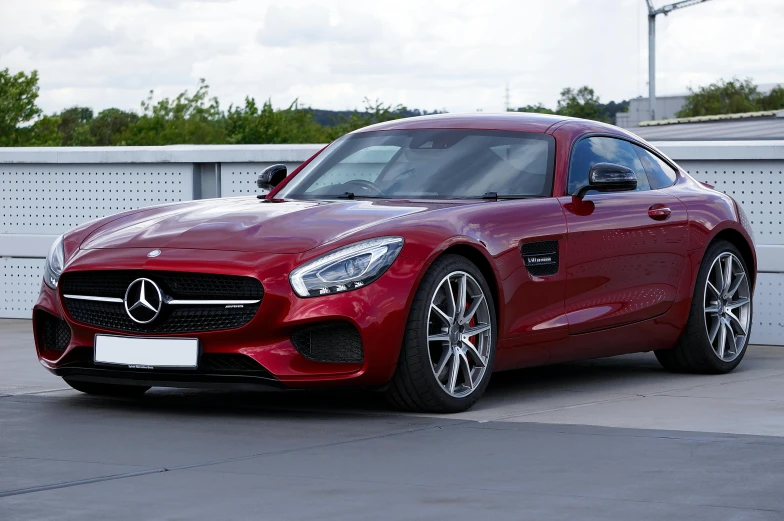 a red mercedes benz sports car parked in front of a fence