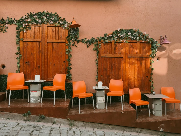 outdoor area with many orange chairs and table and doors