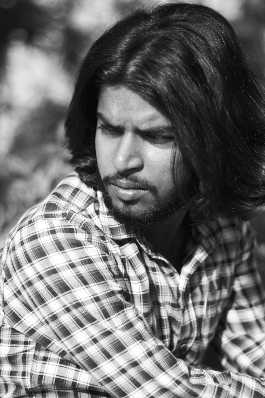 a black and white image of a man with long hair in a plaid shirt