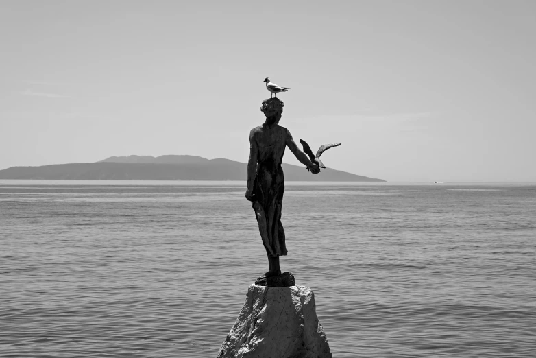 a statue holding a bird and standing on a rock