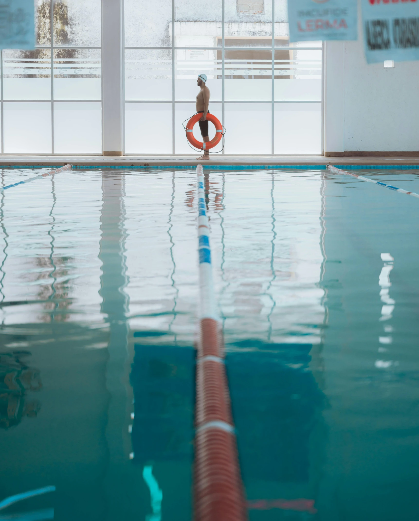 a person with an inflatable body standing at the edge of an indoor swimming pool