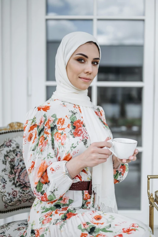 a young woman in a floral dress is drinking out of a mug